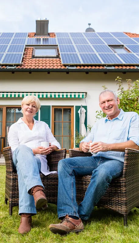 Familie vor einem energieeffizienten Haus mit Solarmodulen